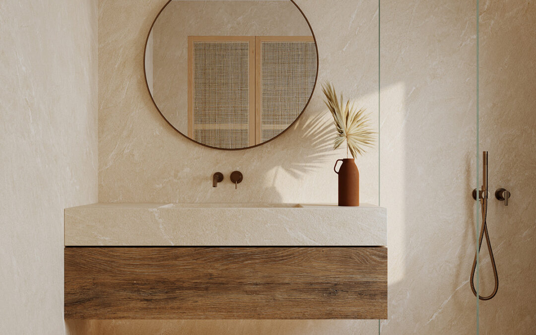 Baño efecto mármol en porcelánico de gran formato con lavabo integrado, grifería empotrada y espejo redondo, ambiente mediterráneo sereno.
