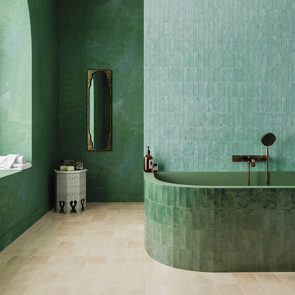Pared de baño revestida con zellige verde artesanal de brillo irregular junto a bañera, estilo mediterráneo.