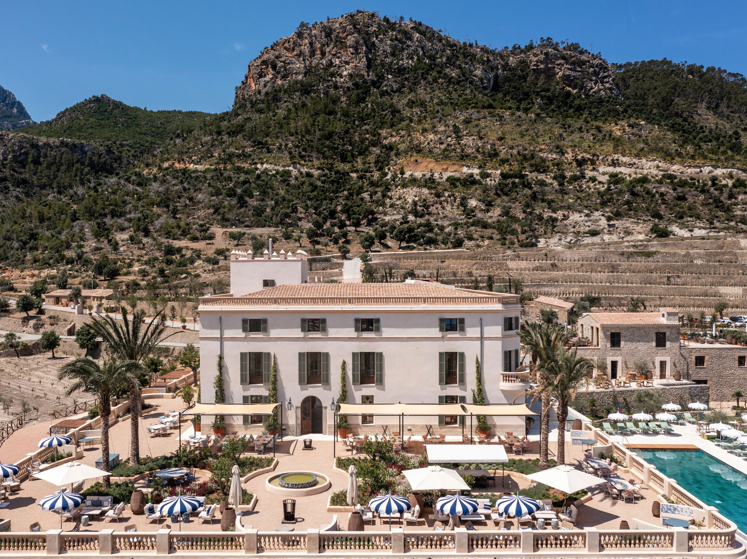 Fassade des Hotels Son Bunyola mit dem Pool und der Serra de Tramuntana im Hintergrund