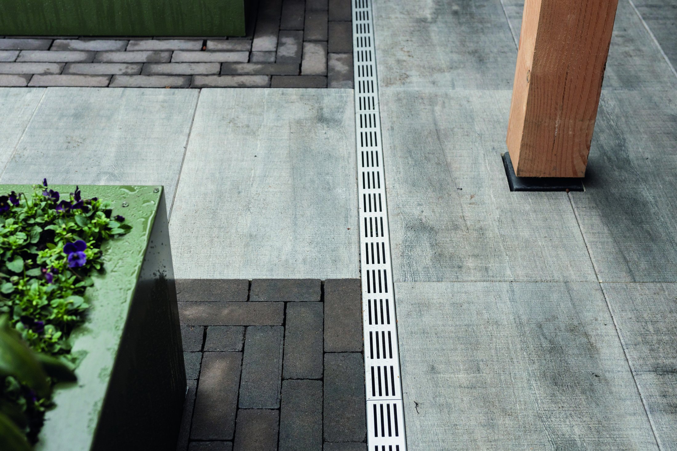 Drainage channel set flush between a terrace floor and a paved area