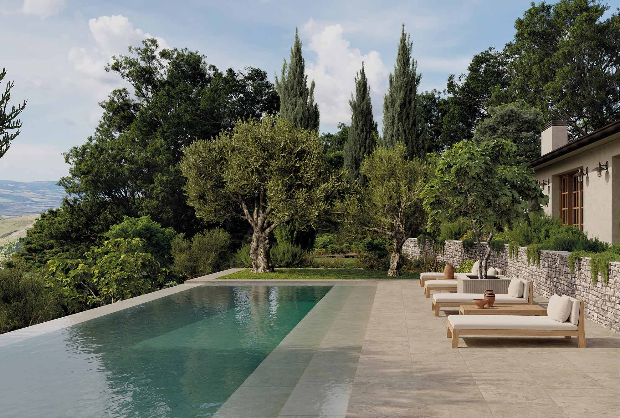 Terraza mediterránea con piscina desbordante, olivos y cipreses, pavimentada con gres efecto piedra en tono arena.